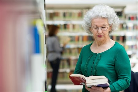 simsearch:400-06107800,k - Portrait of old retired woman choosing book in library and taking it from shelf Photographie de stock - Aubaine LD & Abonnement, Code: 400-06107351