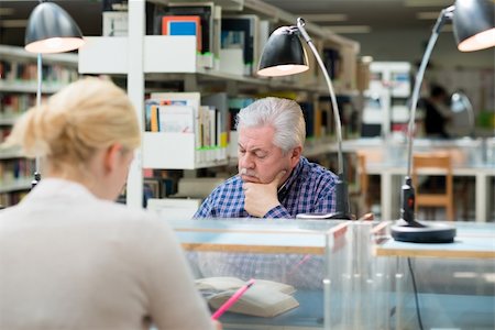 simsearch:400-06107800,k - Elderly man studying among young college students in library and taking notes Photographie de stock - Aubaine LD & Abonnement, Code: 400-06107645