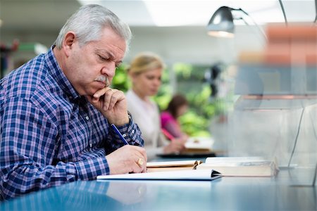 simsearch:400-06107800,k - Elderly man studying with a group of young college students in library and taking notes Photographie de stock - Aubaine LD & Abonnement, Code: 400-06107647