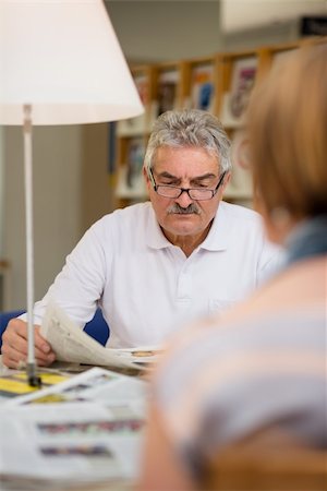 simsearch:400-06107800,k - Retired senior people, old man reading news and magazines with wife in library Photographie de stock - Aubaine LD & Abonnement, Code: 400-06107801