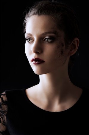 close up portrait of very beautiful young lady actrees over a dark background with dirty make up and fashion light, she is turned of three quarters at right and looks in front of her Stock Photo - Budget Royalty-Free & Subscription, Code: 400-06103703