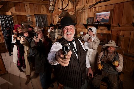 simsearch:400-06097059,k - Laughing man with old west gang point guns in a saloon Stock Photo - Budget Royalty-Free & Subscription, Code: 400-06136060