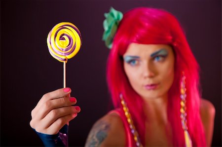 simsearch:400-05219431,k - Girl with pink hair holding lollipop, focus on candy Fotografie stock - Microstock e Abbonamento, Codice: 400-06136111