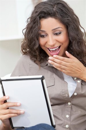 smiling young latina models - Beautiful young Latina Hispanic woman laughing, relaxing and using a tablet computer Stock Photo - Budget Royalty-Free & Subscription, Code: 400-06136728