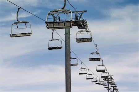 ski hill with chair lift - Idle lift chairs on cloudy blue sky. Foto de stock - Super Valor sin royalties y Suscripción, Código: 400-06138313