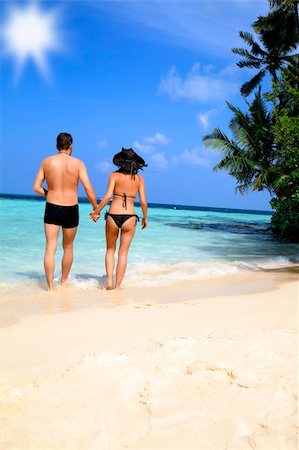 Loving couple in swimsuits holding hands walking away from the camera at the waters edge on a tropical beach Stock Photo - Budget Royalty-Free & Subscription, Code: 400-06138633