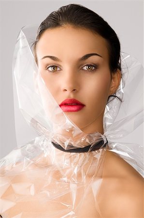 beauty portrait of young brunette with red lips and cellophane around her face, she is in front of the camera and looks in to the lens Fotografie stock - Microstock e Abbonamento, Codice: 400-06138649