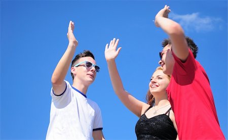 Three happy friends interracial teenage boys and girl giving five, outdoor against summer blue sky Stock Photo - Budget Royalty-Free & Subscription, Code: 400-06139338