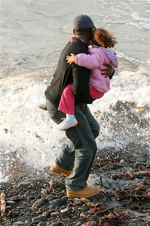 Man holding a little girl in his arms and jumping away from the surf on a beach. Stock Photo - Budget Royalty-Free & Subscription, Code: 400-06133747