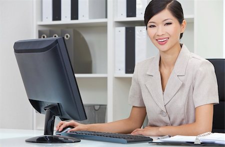 Beautiful young Asian Chinese woman or businesswoman in smart business suit sitting at a desk in an office using a computer Stock Photo - Budget Royalty-Free & Subscription, Code: 400-06140750