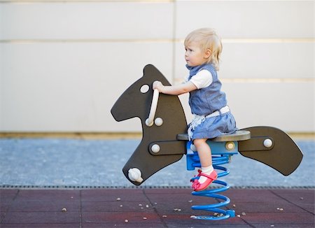 Happy baby swinging on horse on playground. Side view Stock Photo - Budget Royalty-Free & Subscription, Code: 400-06141186
