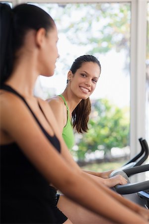 simsearch:400-07554888,k - Young women talking and laughing while working out on exercise  bicycles in wellness club Foto de stock - Super Valor sin royalties y Suscripción, Código: 400-06143006