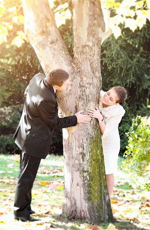 Young couple playing hide and seek around a tree Stock Photo - Budget Royalty-Free & Subscription, Code: 400-06143052