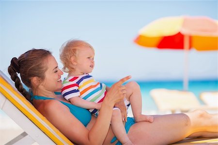 simsearch:400-06639191,k - Mother with baby laying on sunbed and pointing on copy space Stock Photo - Budget Royalty-Free & Subscription, Code: 400-06174347