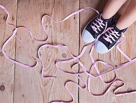 superação de obstáculos - The shoe tie puzzle - child feet and long twisted shoelaces on wooden floor Foto de stock - Royalty-Free Super Valor e Assinatura, Número: 400-06174629