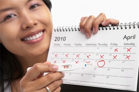 Asian lady holding pregnancy test device pointing it to the calendar Photographie de stock - Aubaine LD & Abonnement, Code: 400-06176371