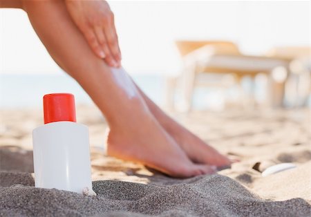 Bottle of sun block and female applying creme on leg on beach Stock Photo - Budget Royalty-Free & Subscription, Code: 400-06177576