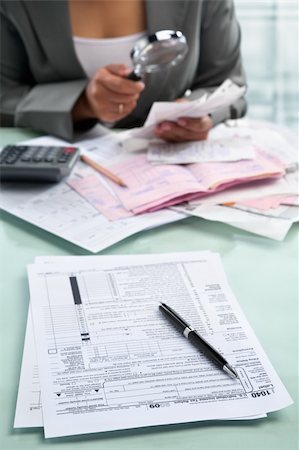 pile hands bussiness - Tax form and unrecognizable businesswoman in the background using magnifying glass Stock Photo - Budget Royalty-Free & Subscription, Code: 400-06177970