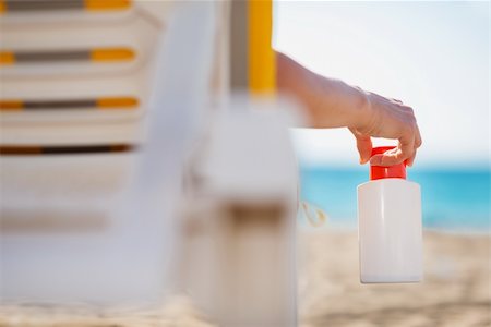simsearch:400-06639191,k - Closeup on bottle of sun screen in hand of female laying on sunbed Stock Photo - Budget Royalty-Free & Subscription, Code: 400-06178686