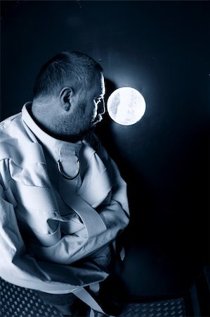 Photo of an insane man in his forties wearing a straitjacket standing in a cell of an asylum with the light from the hallway streaming in. Photographie de stock - Aubaine LD & Abonnement, Code: 400-06179543