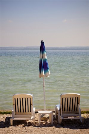 Two beach chairs and a closed umbrella on Garda Lake, Italy Foto de stock - Super Valor sin royalties y Suscripción, Código: 400-06172852