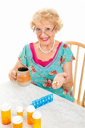 pillbox - Smiling senior lady cheerfully takes her prescriptions and suppliments.  White background. Stock Photo - Budget Royalty-Free & Subscription, Code: 400-06172892