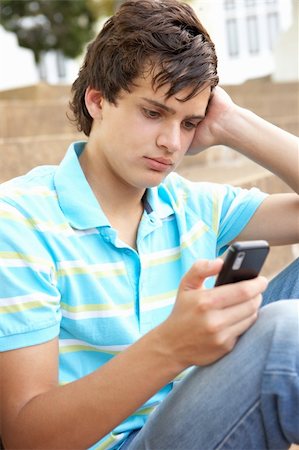 simsearch:400-06204445,k - Unhappy Male Teenage Student Sitting Outside On College Steps Using Mobile Phone Foto de stock - Royalty-Free Super Valor e Assinatura, Número: 400-06204184