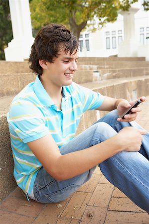 simsearch:400-06204445,k - Male Teenage Student Sitting Outside On College Steps Using Mobile Phone Foto de stock - Royalty-Free Super Valor e Assinatura, Número: 400-06204182