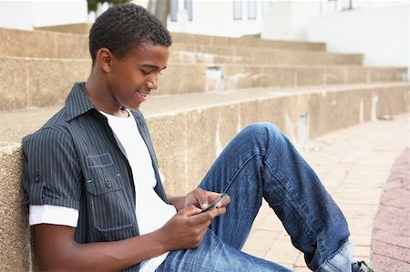 simsearch:400-06204445,k - Male Teenage Student Sitting Outside On College Steps Using Mobile Phone Foto de stock - Royalty-Free Super Valor e Assinatura, Número: 400-06204198