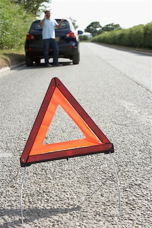 Driver Broken Down On Country Road With Hazard Warning Sign In Foreground Foto de stock - Super Valor sin royalties y Suscripción, Código: 400-06205204