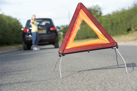 Female Driver Broken Down On Country Road With Hazard Warning Sign In Foreground Foto de stock - Super Valor sin royalties y Suscripción, Código: 400-06205219