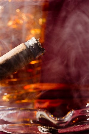 simsearch:400-05292494,k - Close-up selective focus of a burning cigar with a glass of whiskey in the background. Stock Photo - Budget Royalty-Free & Subscription, Code: 400-06206942