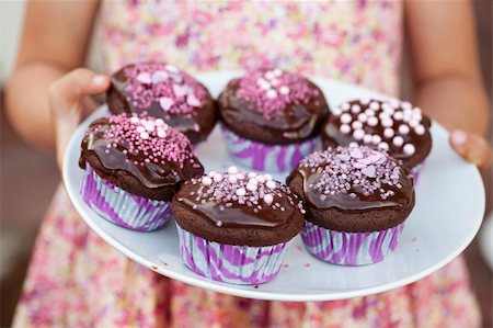 pink choc cake - Close-up of hands holding a plate of delicious chocolate cupcakes with chocolate icing and sprinkles Stock Photo - Budget Royalty-Free & Subscription, Code: 400-06207007