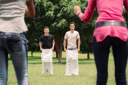 friends race - Friends having fun, young men playing sack race in city park with women clapping hands and laughing Stock Photo - Budget Royalty-Free & Subscription, Code: 400-06207165