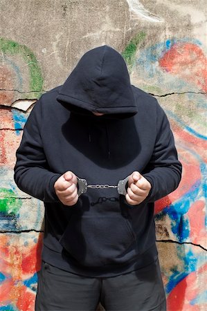 simsearch:400-05898292,k - Man in handcuffs on a wall background Foto de stock - Super Valor sin royalties y Suscripción, Código: 400-06207162