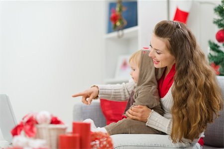 Happy young mother spending Christmas with baby and pointing on laptop Stock Photo - Budget Royalty-Free & Subscription, Code: 400-06208363