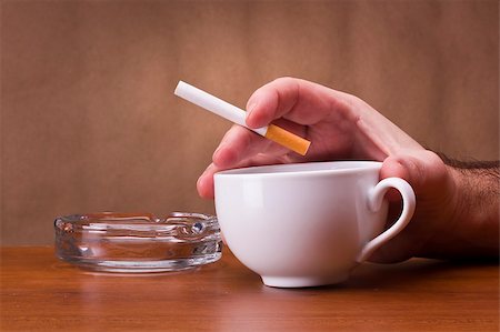 Hand holding a cigarette and a cup ashtray. Stock Photo - Budget Royalty-Free & Subscription, Code: 400-06208593