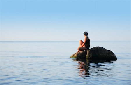 Svelte adult woman sitting on big stone in the sea and looking to horizon Foto de stock - Super Valor sin royalties y Suscripción, Código: 400-06201597