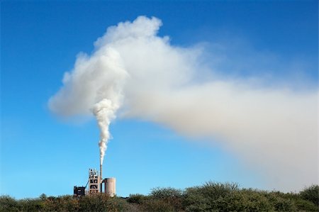Smoke from an industrial plant drifting in the wind against a blue sky Stock Photo - Budget Royalty-Free & Subscription, Code: 400-06201890