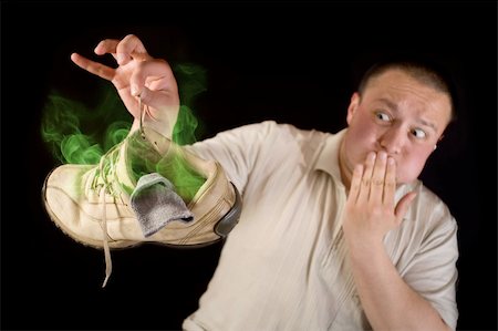 plugging nose - Shocked man holding smelling shoe isolated on black background Stock Photo - Budget Royalty-Free & Subscription, Code: 400-06202459