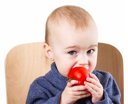 young child eating tomatoes in high chair. neutral background Foto de stock - Royalty-Free Super Valor e Assinatura, Número: 400-06203109