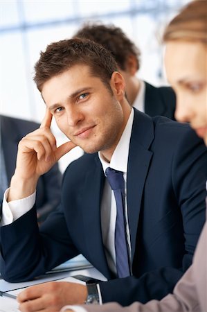 shyshka (artist) - Young smiling businessman holding hand near head in the office with colleagues. Photographie de stock - Aubaine LD & Abonnement, Code: 400-06329096