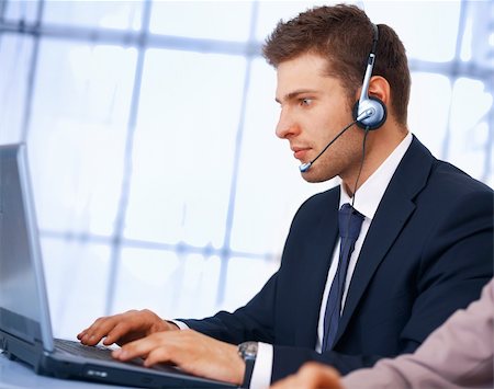 simsearch:400-05244427,k - Closeup of a businessman with headset. He is working on laptop Stock Photo - Budget Royalty-Free & Subscription, Code: 400-06329119