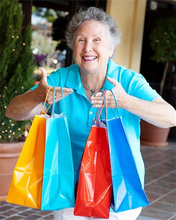 Senior woman addicted to shopping, holding up a handful of bags. Stock Photo - Budget Royalty-Free & Subscription, Code: 400-06331714