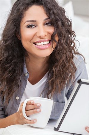 simsearch:400-04340722,k - Beautiful young Latina Hispanic woman smiling, relaxing and drinking a cup of coffee or tea using tablet computer Stock Photo - Budget Royalty-Free & Subscription, Code: 400-06332110