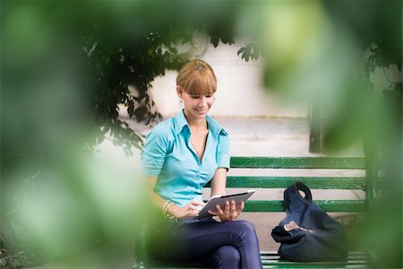 students tablets outside - Portrait of happy young female college student typing on digital tablet computer and sitting on bench in city park Stock Photo - Budget Royalty-Free & Subscription, Code: 400-06333548