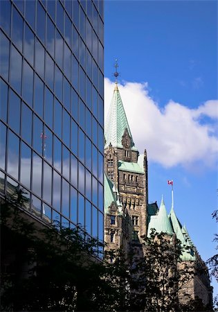 The canadian Parliament Confederation building seen behind a modern glass building in Ottawa, Canada. Foto de stock - Super Valor sin royalties y Suscripción, Código: 400-06364010