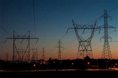 simsearch:400-04838002,k - A long line of electrical transmission towers (electricity pylons) carrying high voltage lines in the city at sunset. Foto de stock - Royalty-Free Super Valor e Assinatura, Número: 400-06367395