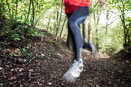 running with running shoes on a running track - Male trail runner running in the forest on a trail. Red shirt and black pants. Summer season. Slight blur in runner to show motion. Horizontal composition. Stock Photo - Budget Royalty-Free & Subscription, Code: 400-06367454