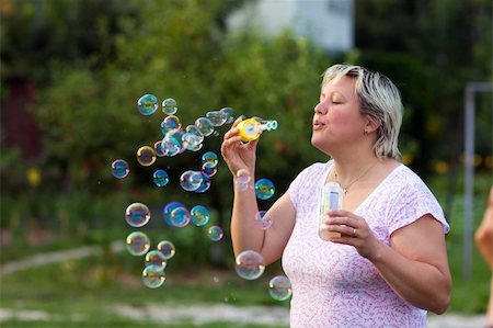 Middle-aged Woman blowing bubbles outdoors Stock Photo - Budget Royalty-Free & Subscription, Code: 400-06387628